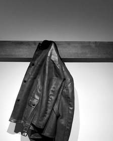 Chaqueta de cuero marrón colgada de un riel de madera