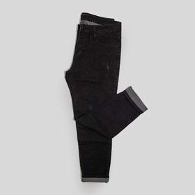Pantalón de mezclilla negra doblado sobre un fondo gris