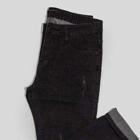 Pantalón de mezclilla negra doblado sobre un fondo gris