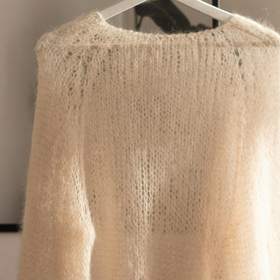 Suéter de mohair claro colgado junto a una cortina