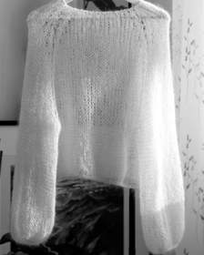 Suéter de mohair claro colgado junto a una cortina