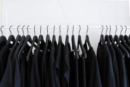 Fila de prendas negras en perchas negras