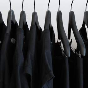 Fila de prendas negras en perchas negras