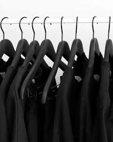 Fila de prendas negras en perchas negras