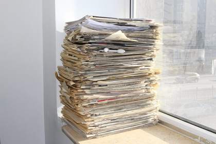 Pila de papeles y revistas junto a una ventana