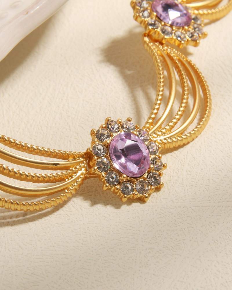Collar dorado con piedras lila sobre una tela color crema