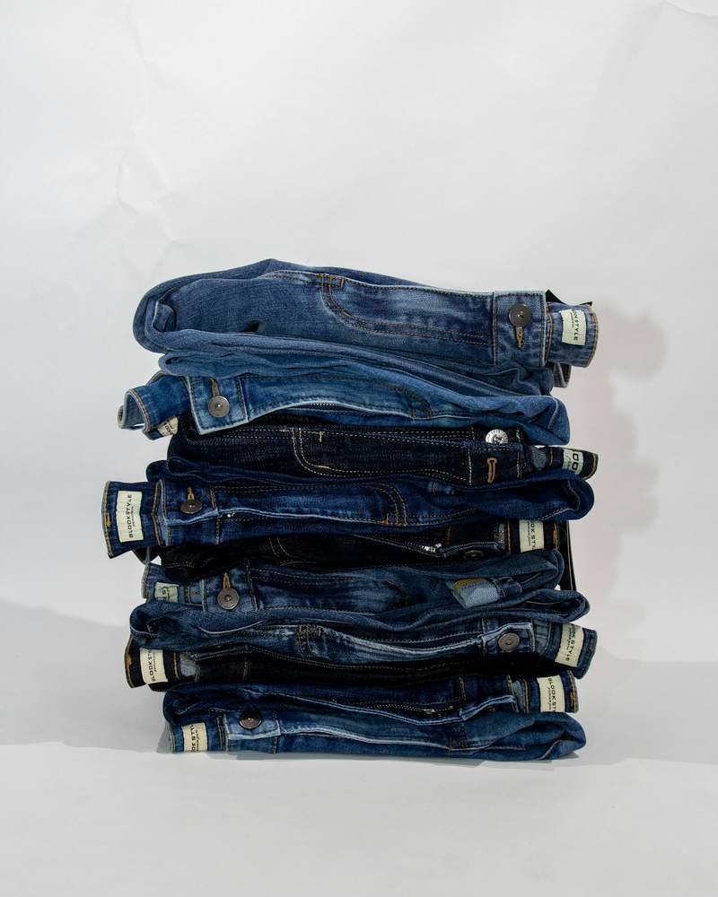 Pila de pantalones de denim doblados sobre fondo claro