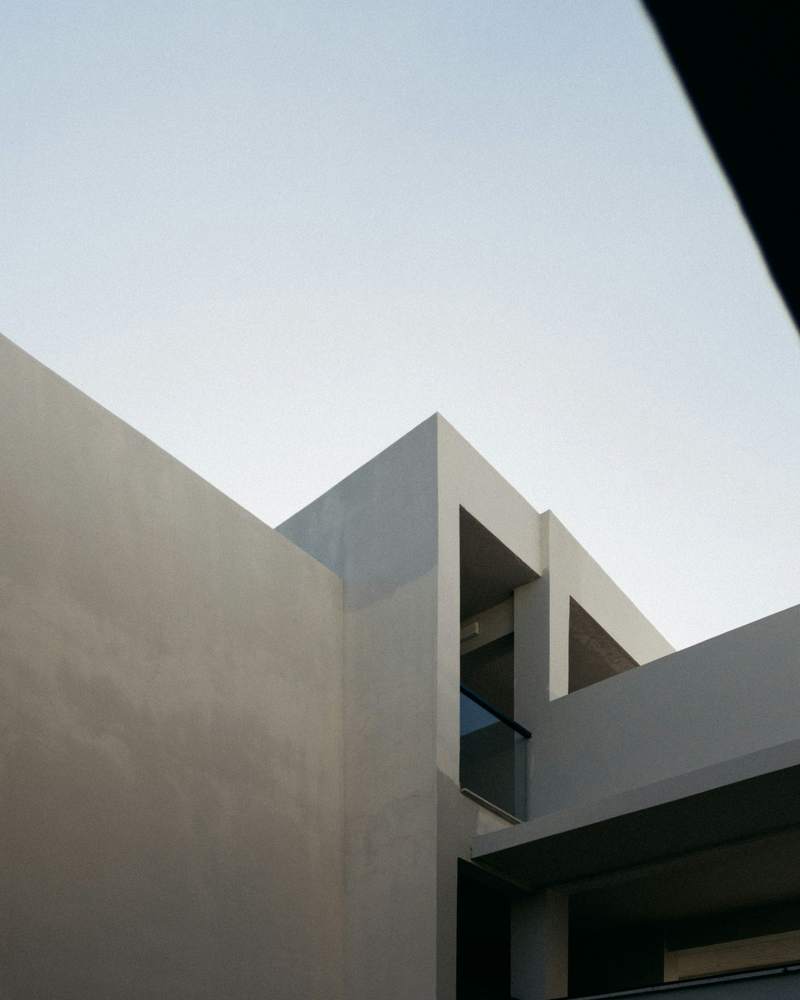 Edificio de hormigón claro con volúmenes geométricos contra el cielo, en blanco y negro