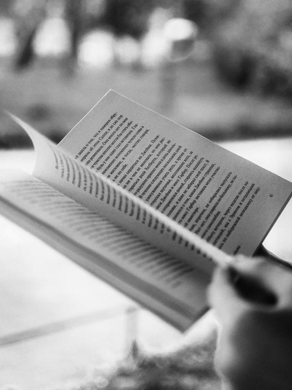 Unas manos pasan las páginas de un libro, en blanco y negro.