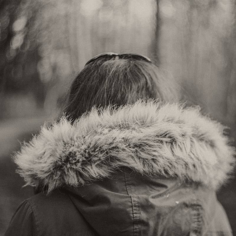 Una persona de espaldas con una capucha con borde de pelo, en blanco y negro cálido