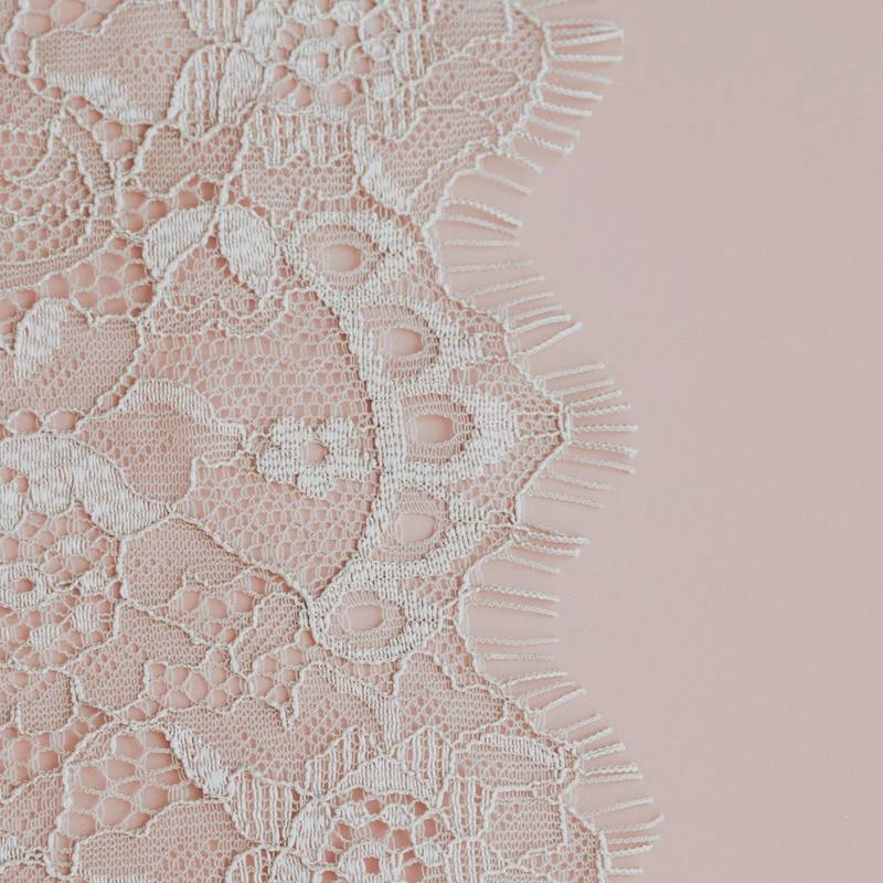 Un encaje blanco sobre un fondo rosa pálido