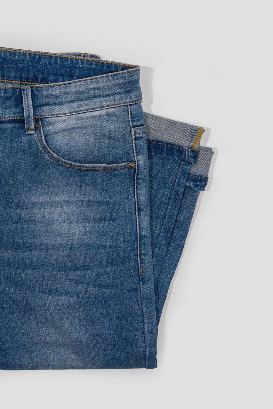 Unos jeans azules doblados sobre un fondo gris claro
