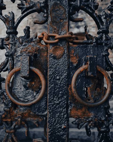 Reja de hierro forjado con argollas oxidadas y una cadena