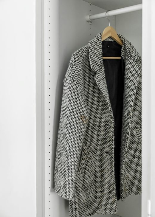 Abrigo de tweed gris y blanco colgado en un armario blanco