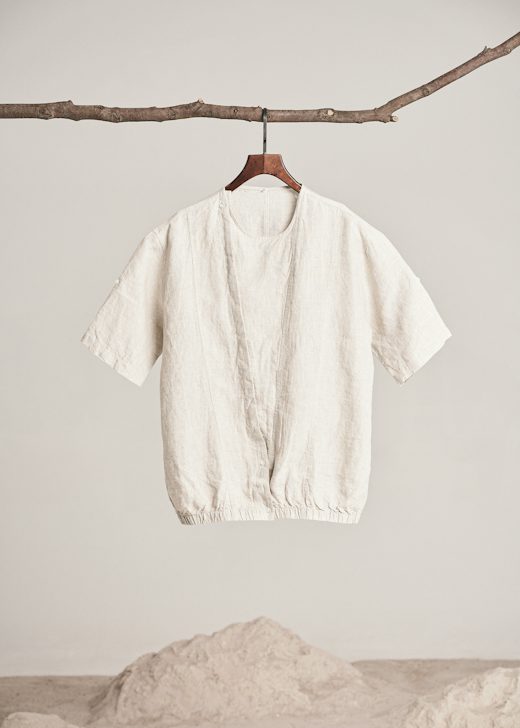 Camisa de lino crudo de cuello redondo y bajo elástico colgada de una rama