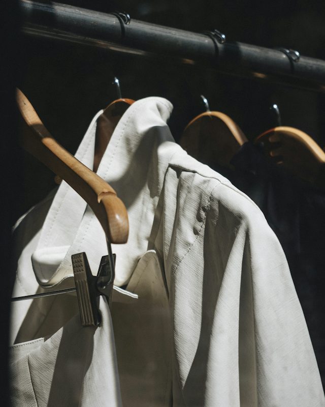 Camisas de lino blanco colgadas de perchas de madera en un riel
