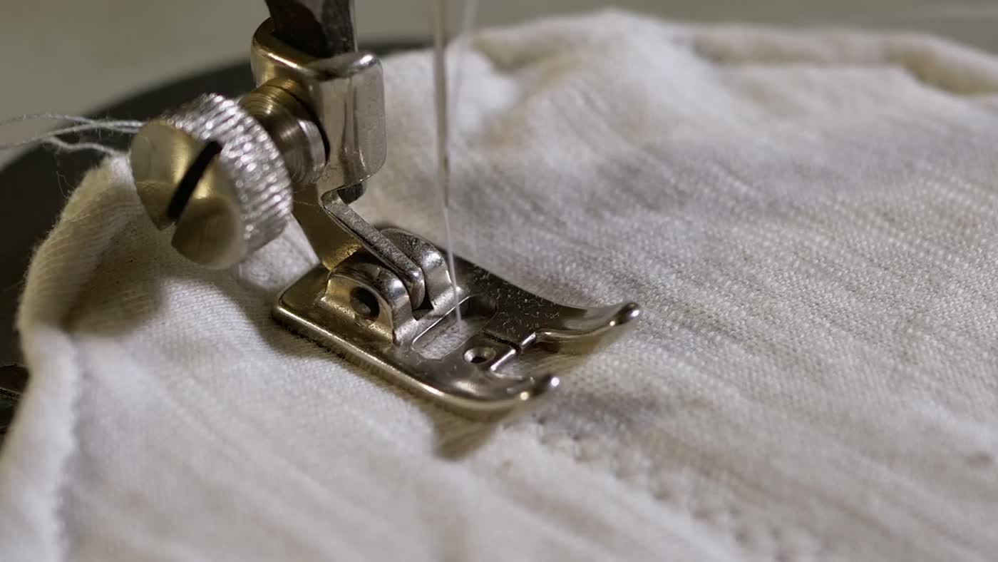 Prensatelas de una máquina de coser sobre tela de lino crudo