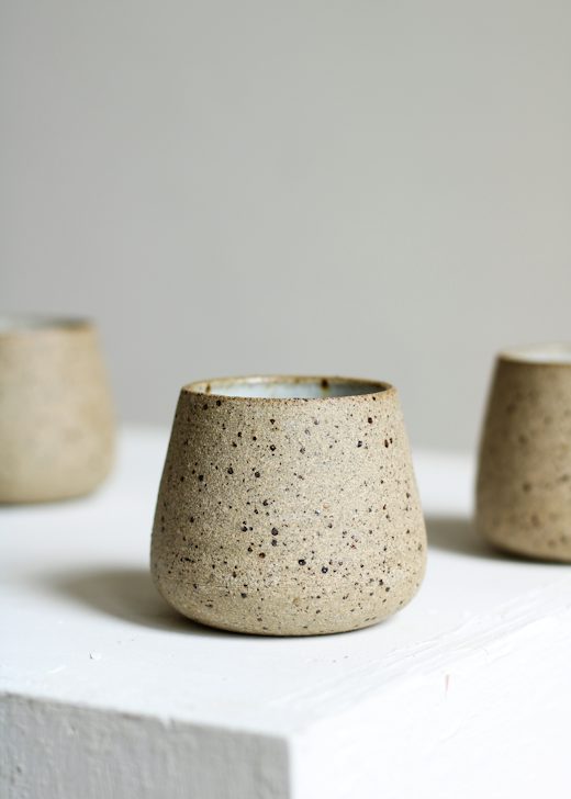 Vaso de gres con pintas oscuras sobre un bloque blanco