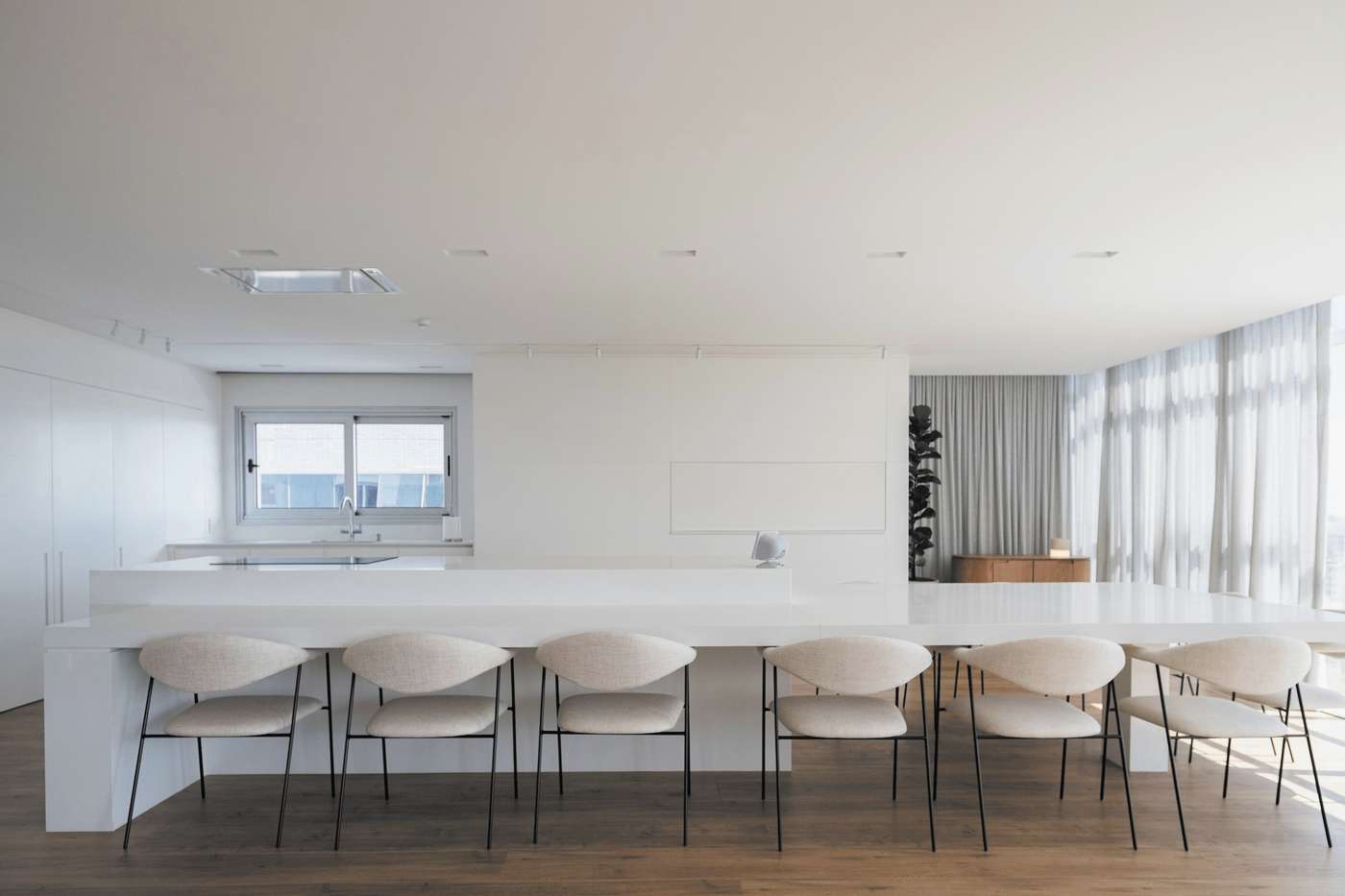 Sala de reuniones blanca con una larga mesa y sillas claras