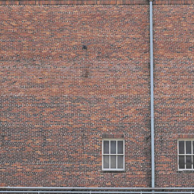 Muro de ladrillo rojo con dos ventanas pequeñas
