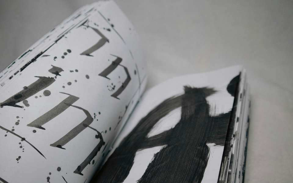 Páginas de un libro con letras pintadas a pincel en negro y gris