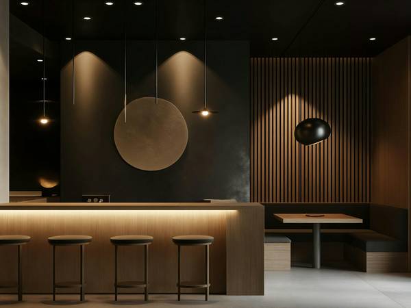 Mostrador oscuro de un café, con taburetes, madera y luz cálida