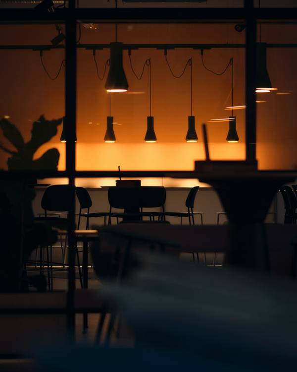 Salón de un café con lámparas colgantes encendidas a contraluz