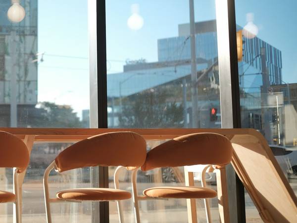 Taburetes junto a una ventana grande de un café, con edificios al fondo