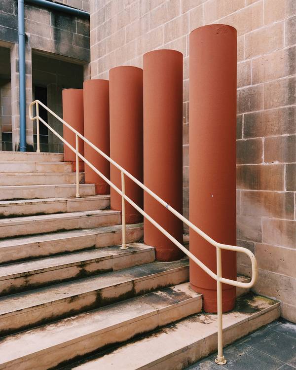 Escalera con baranda junto a una hilera de columnas de color terracota