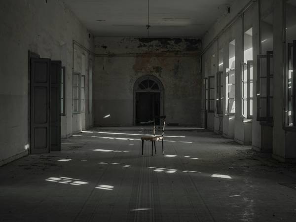 Sala amplia y vacía con puertas altas y manchas de luz en el suelo