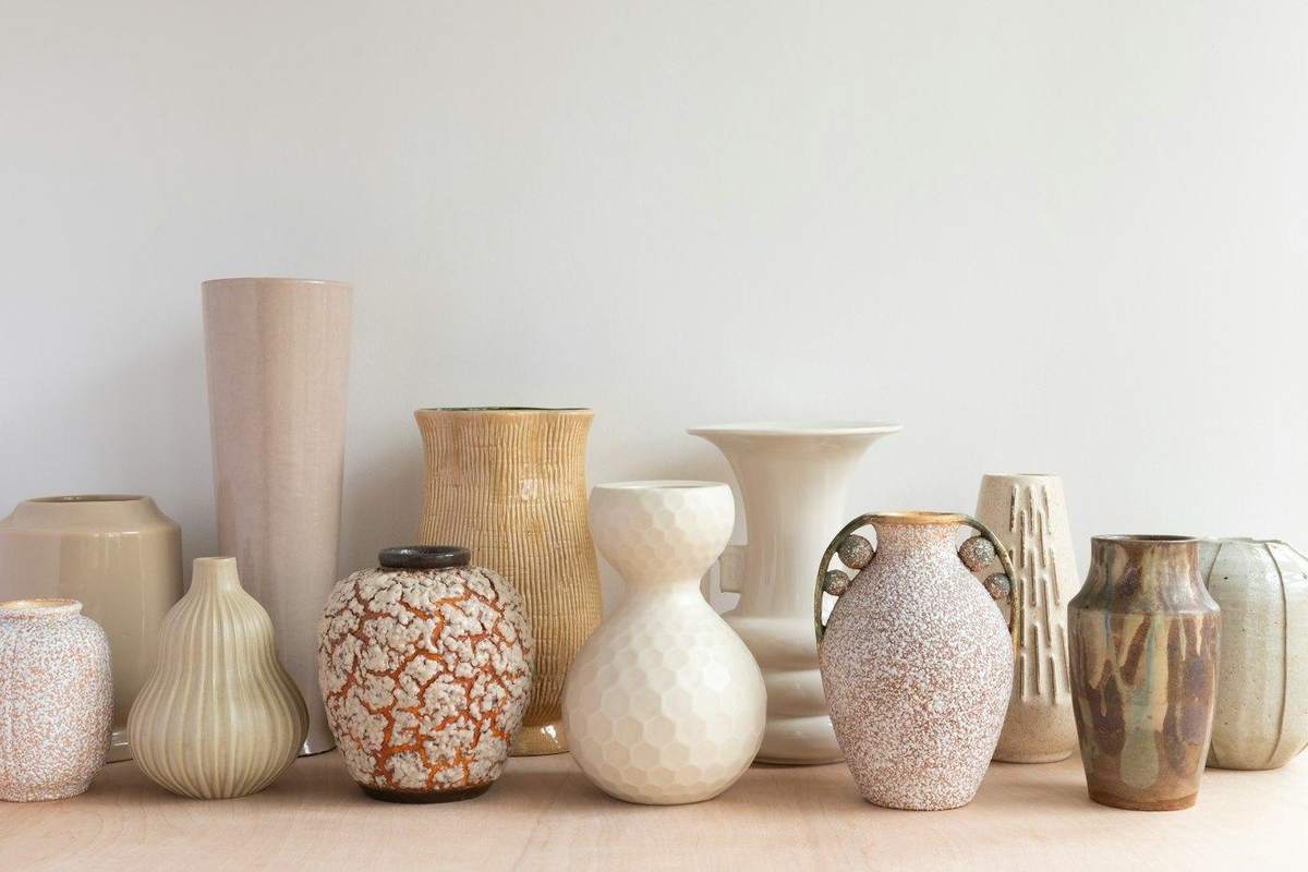 Colección de jarrones claros sobre una repisa de madera