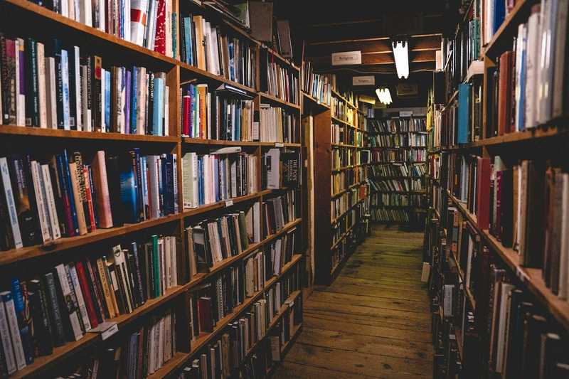 Pasillo largo entre estanterías de madera llenas de libros