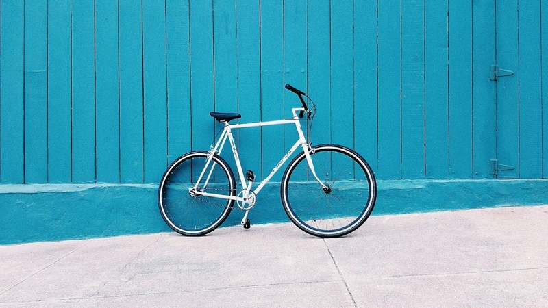 Bicicleta blanca apoyada en un muro azul turquesa