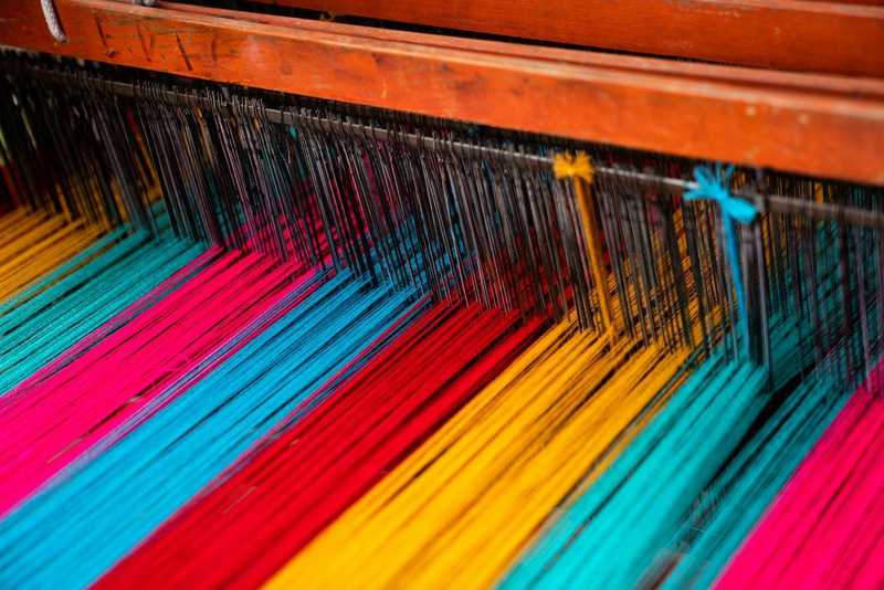 Hilos de colores sobre un telar de madera