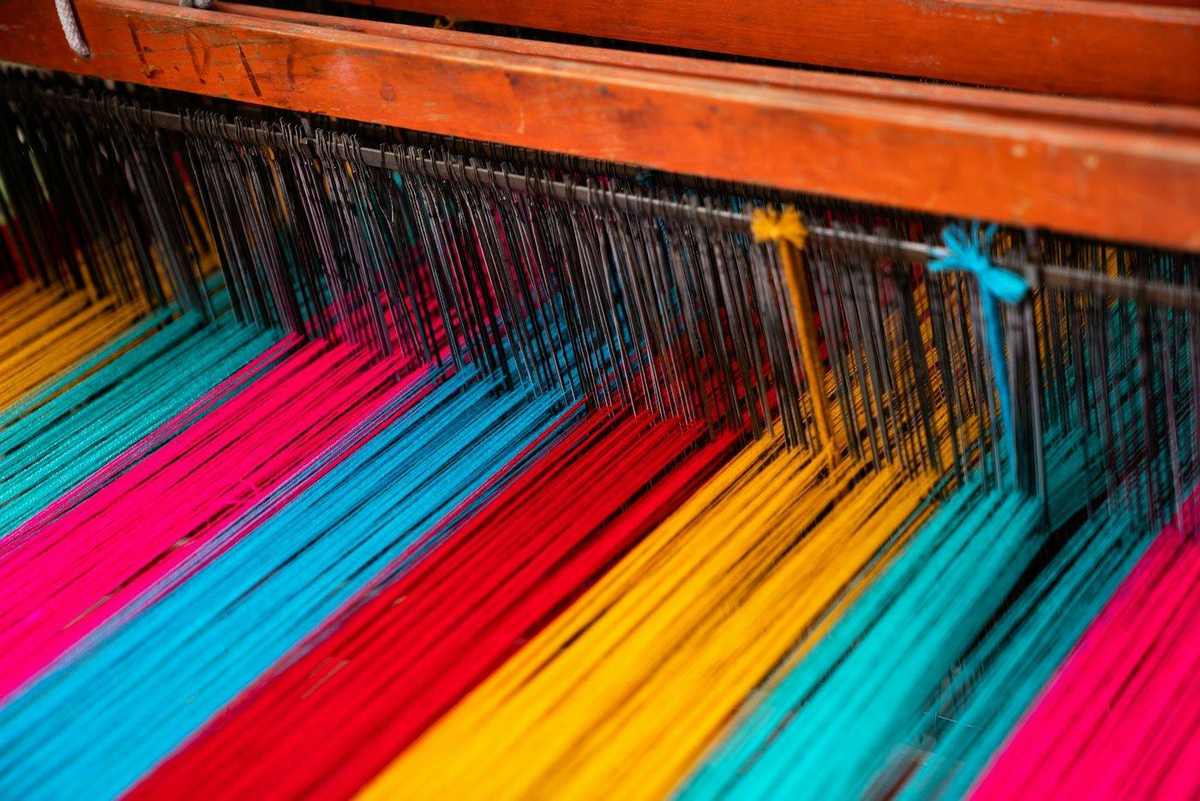 Hilos de colores sobre un telar de madera