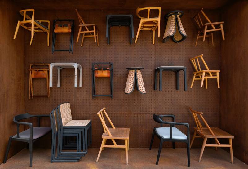 Muro de madera con sillas y taburetes colgados como en una exposición