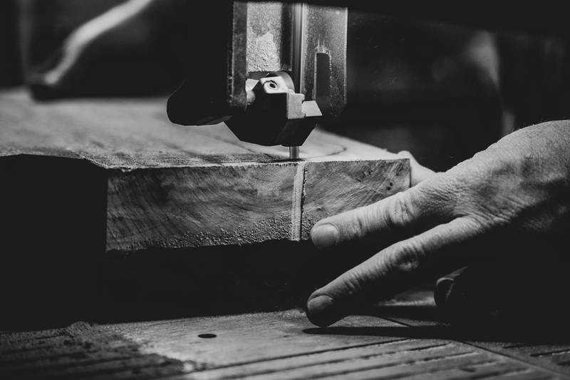 Mano guiando un tablero junto a la sierra, en blanco y negro