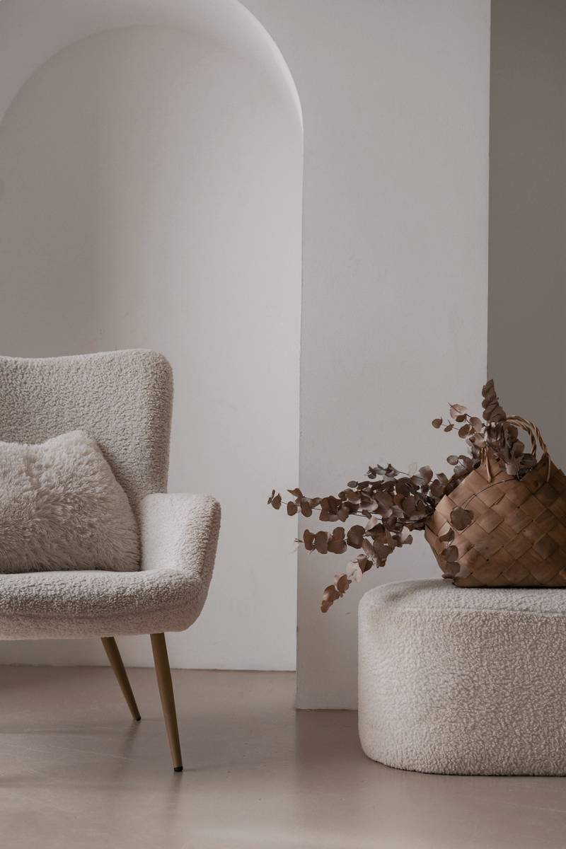Sillón blanco de lana rizada y un jarrón con ramas secas