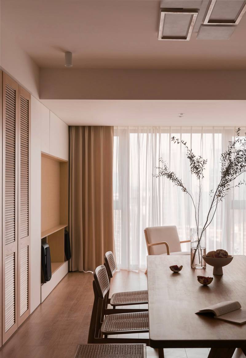 Comedor de madera con cortinas de lino y un jarrón de ramas