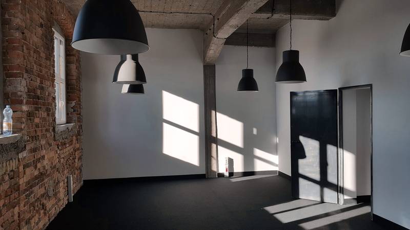 Sala amplia de paredes blancas, ladrillo y lámparas negras