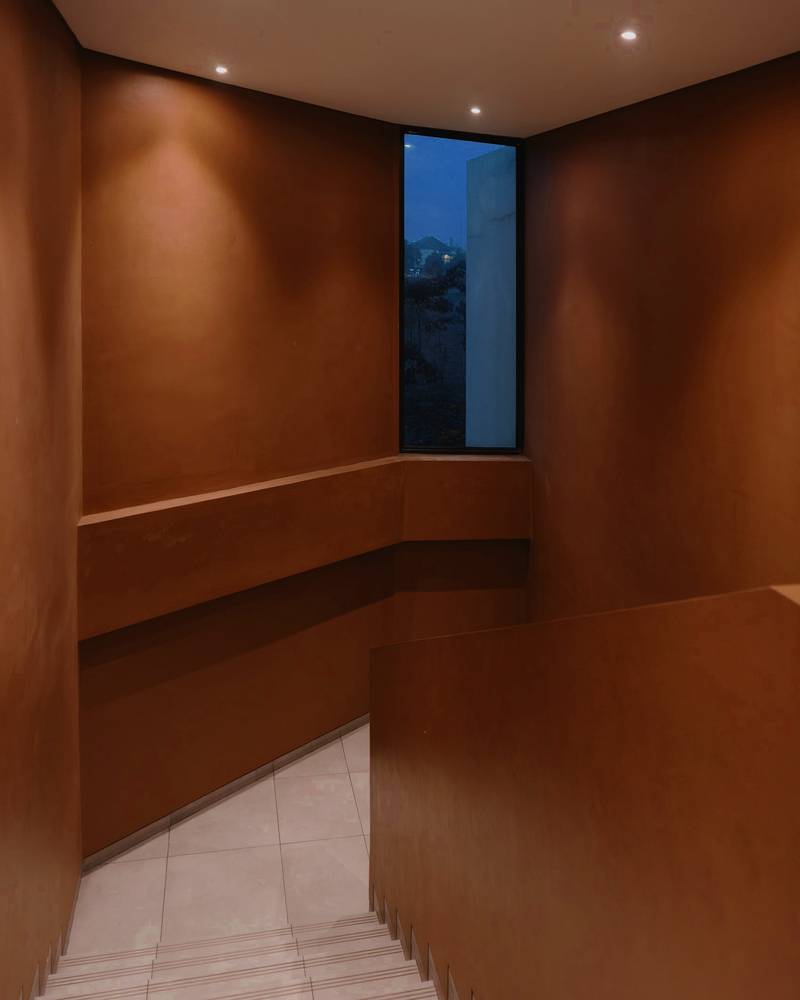 Escalera con muros de madera cobriza y una ventana angosta