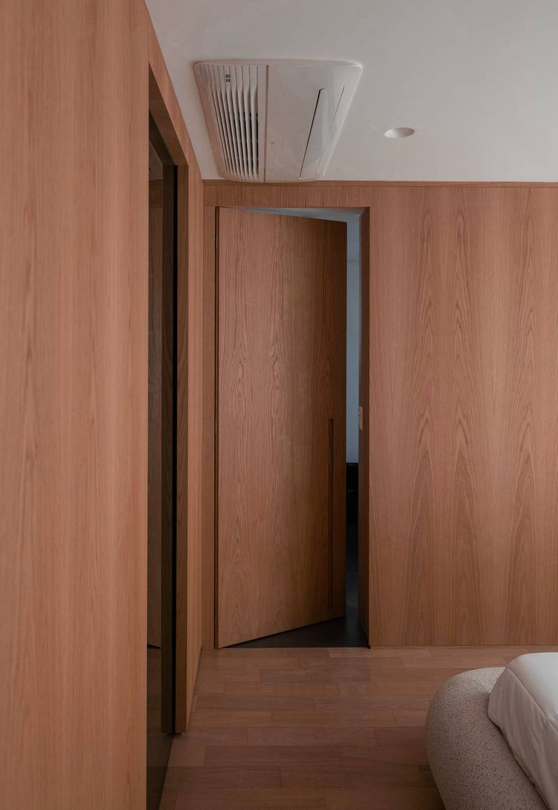 Pasillo con muros de madera clara y una puerta entreabierta
