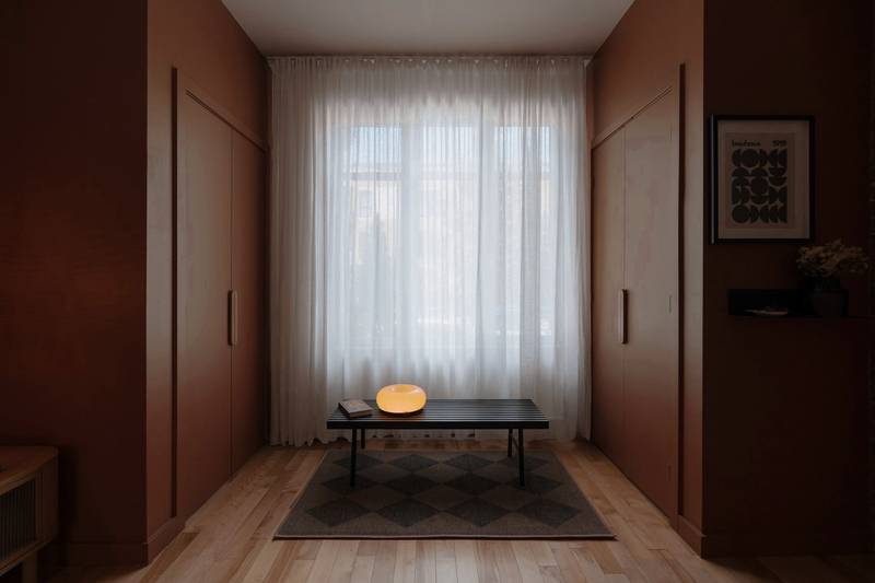 Habitación de muros color vino con cortinas claras y una mesa baja