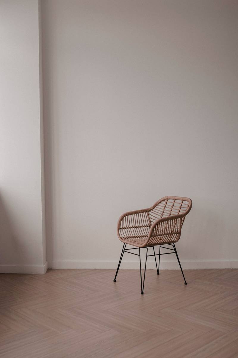 Silla de rejilla al fondo de una habitación vacía con piso en espiga
