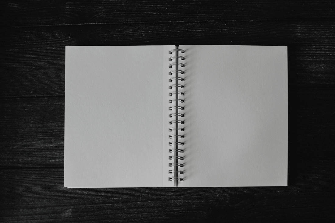 Cuaderno de espiral abierto, visto desde arriba, sobre madera negra