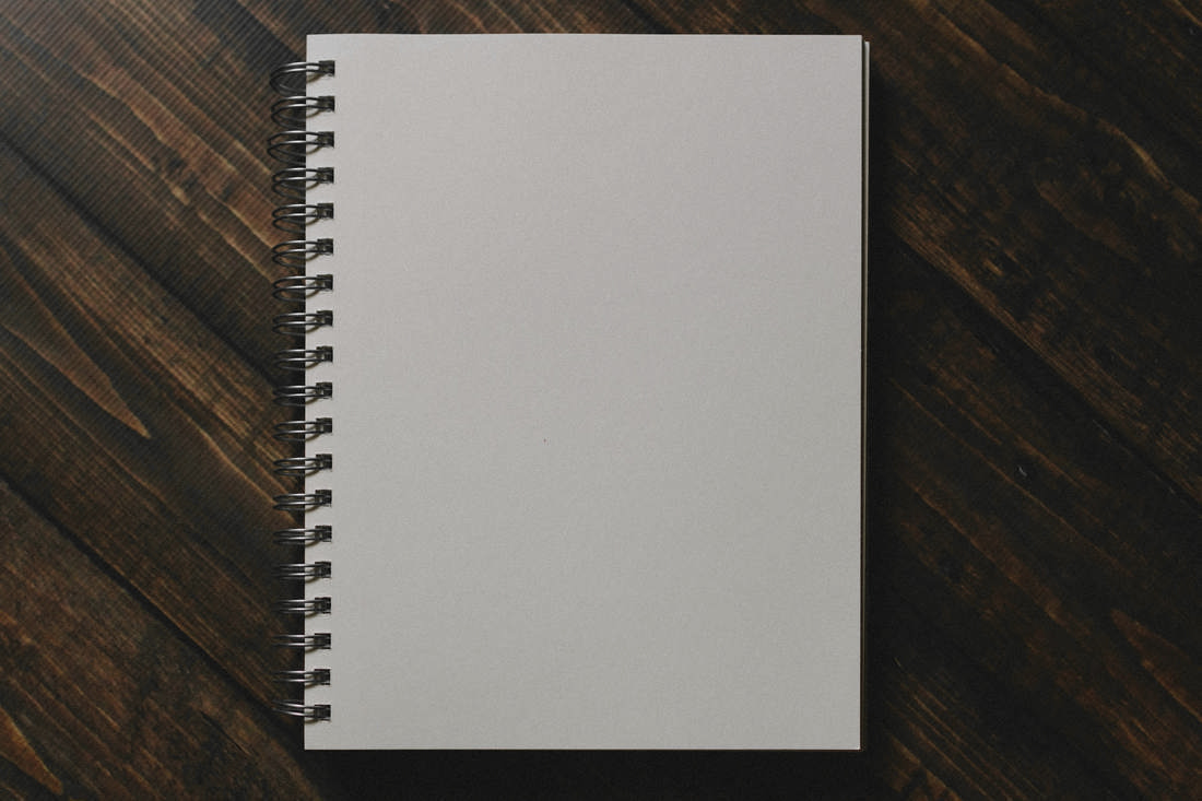 Cuaderno de espiral con tapa clara sobre una mesa de madera marrón