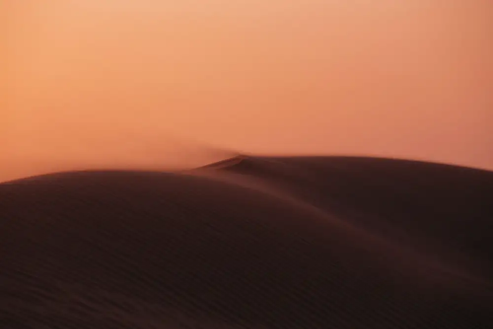 Duna al atardecer bajo un cielo naranja
