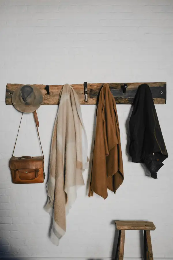 Abrigos, un sombrero y un bolso colgados de una tabla de madera
