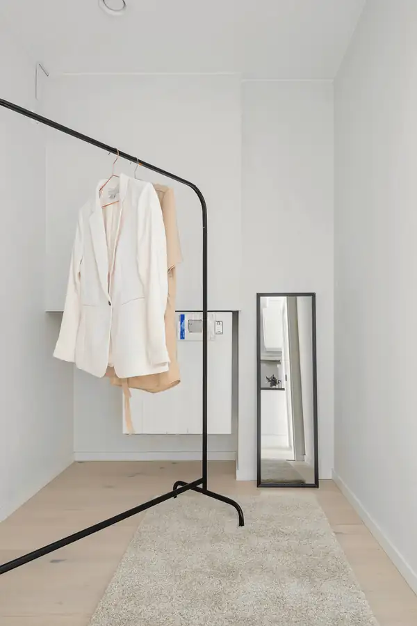Perchero negro con un blazer blanco en una sala clara