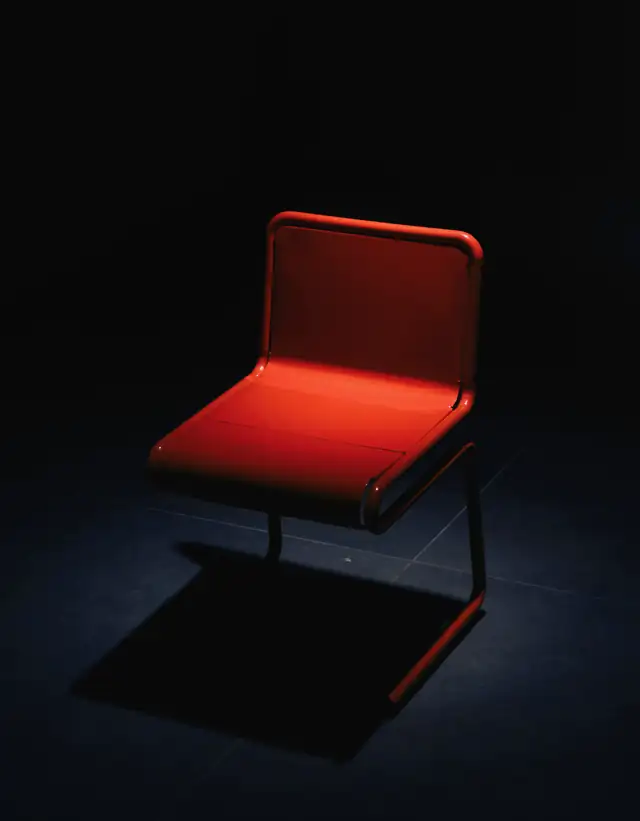 Una silla roja sola en una sala oscura